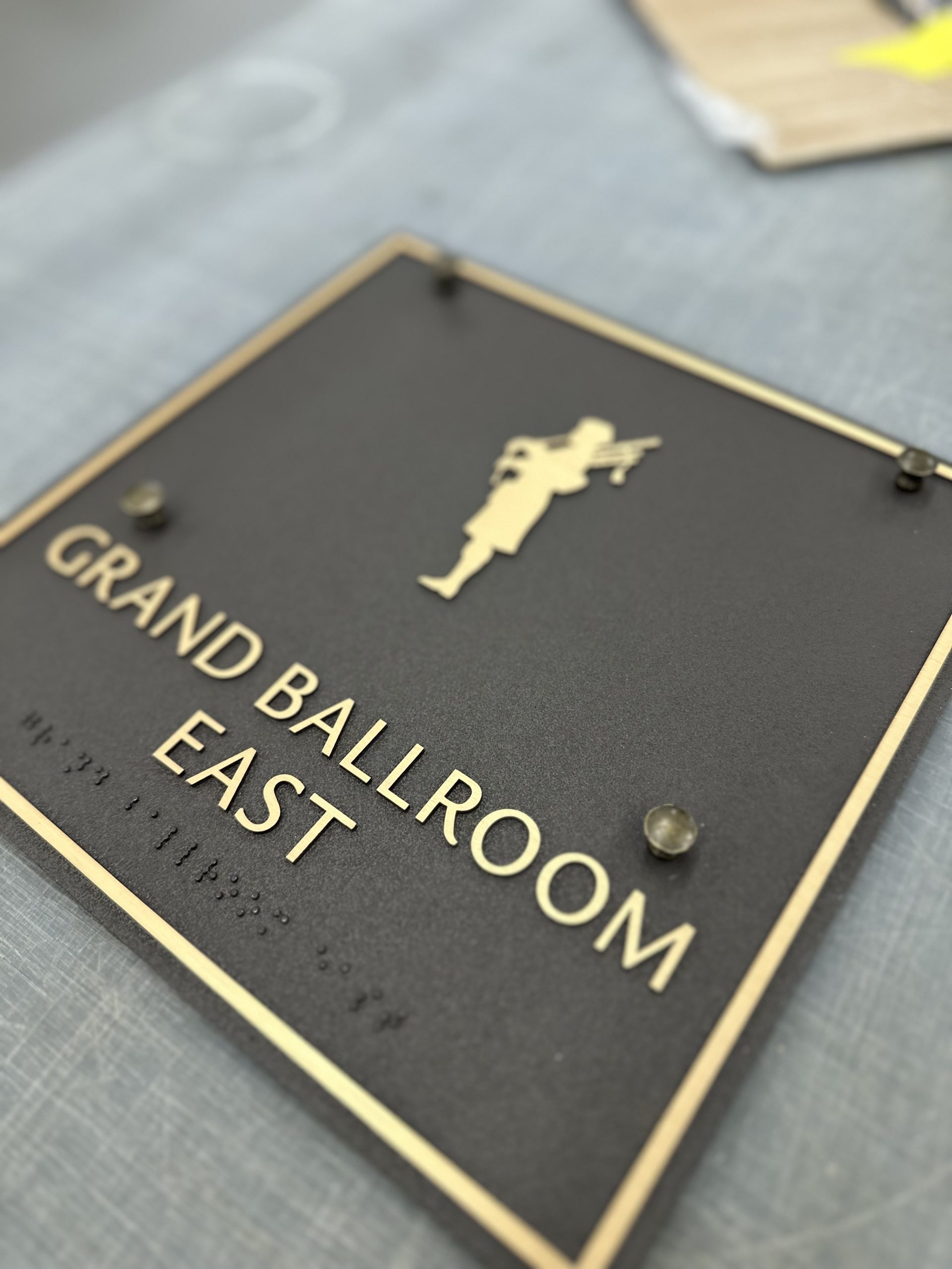 Grand Ballroom East brass plaque at The Lodge at Pebble Beach with ADA-compliant Braille -- CNC-machined by Signworks