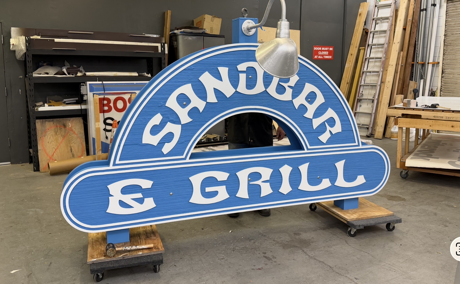 New sandblasted Sandbar and Grill sign with gooseneck light fully assembled in Signworks shop