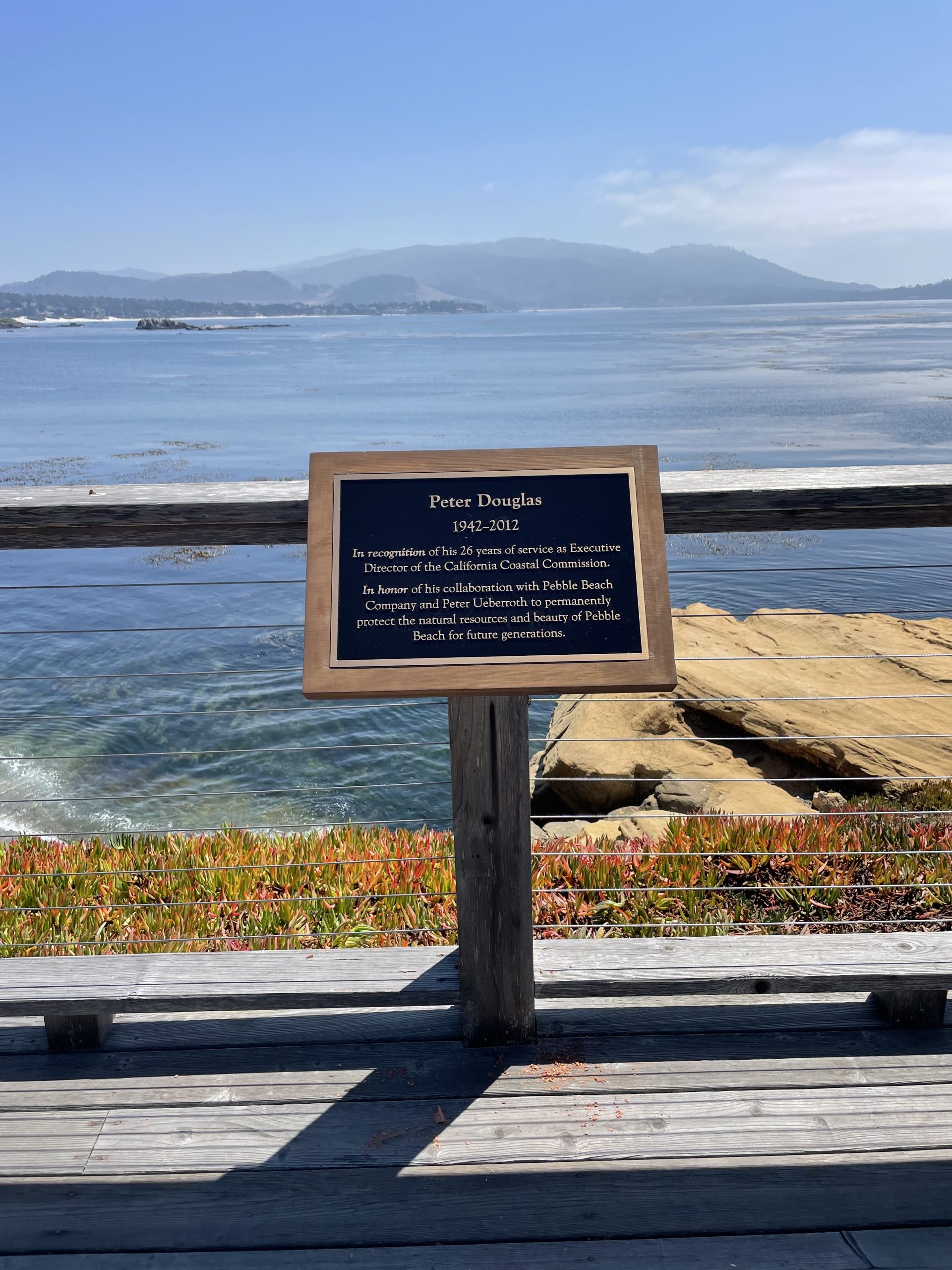 Peter Douglas memorial plaque on a coastal boardwalk overlooking the Pacific Ocean