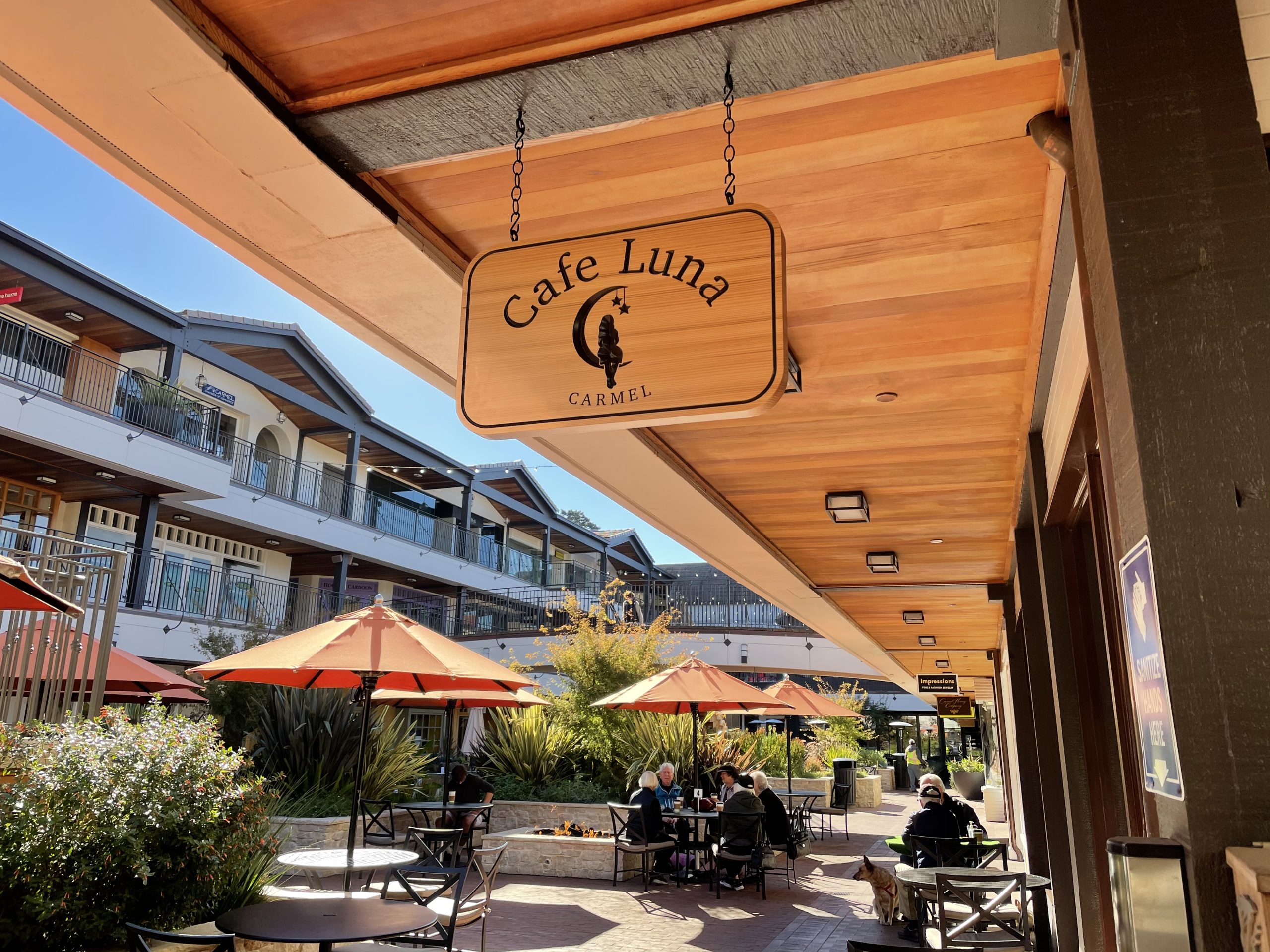 Cafe Luna natural wood hanging sign with chain hardware under cedar ceiling