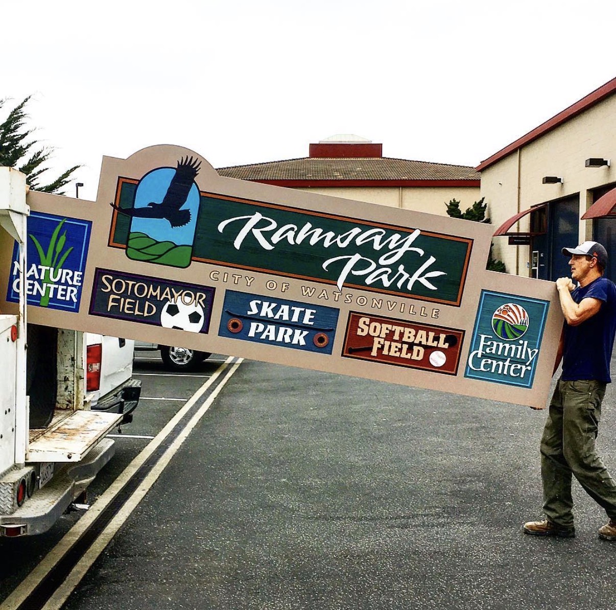 Signworks crew member carrying the finished Ramsay Park sign to the truck for delivery