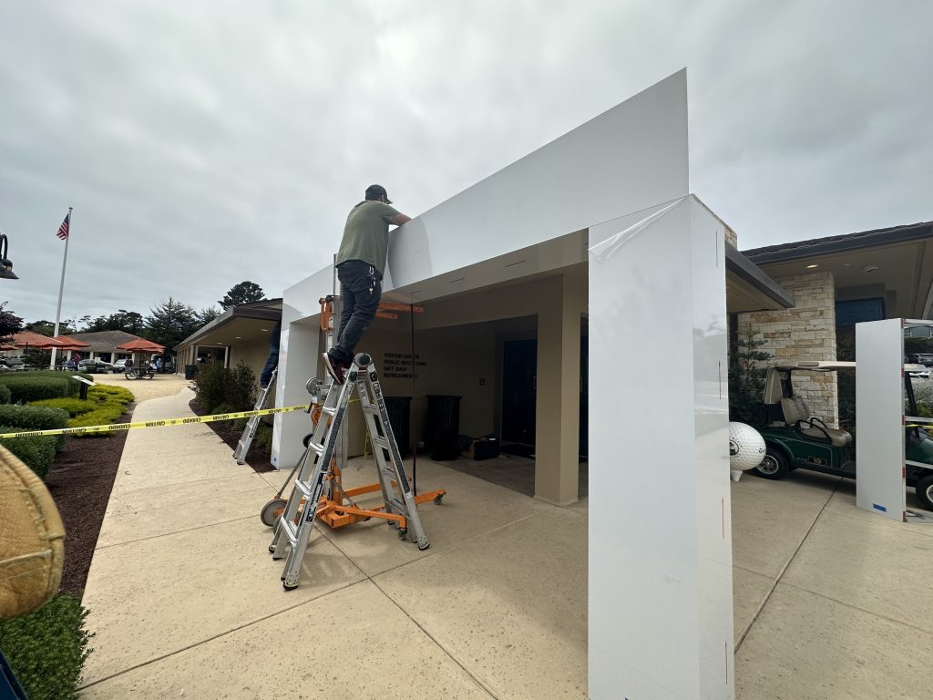 Signworks crew installing signage on event pavilion structure at Pebble Beach golf tournament