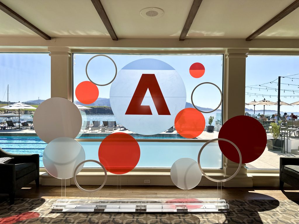 Adobe branded window display graphics with logo and colorful circles at corporate event venue